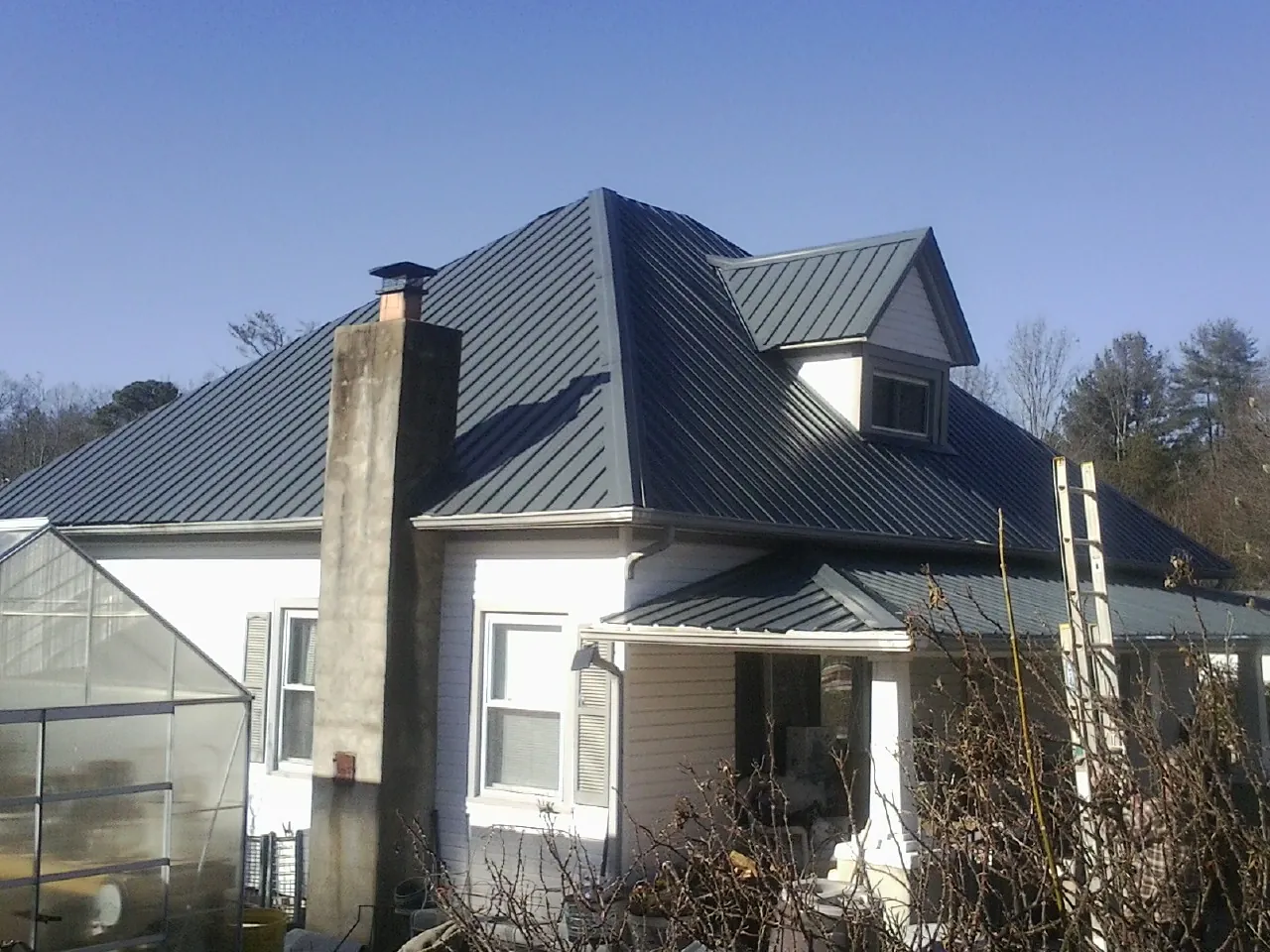 Dark blue standing seam metal roof on a white farmhouse with dormer — Slate & Tile Roof Repair by Roofing Brothers in Picacho