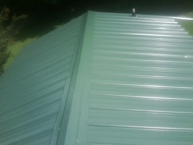 New green metal panels meeting at the ridge of a roof — Flat Roof Repair work by our crew in Picacho