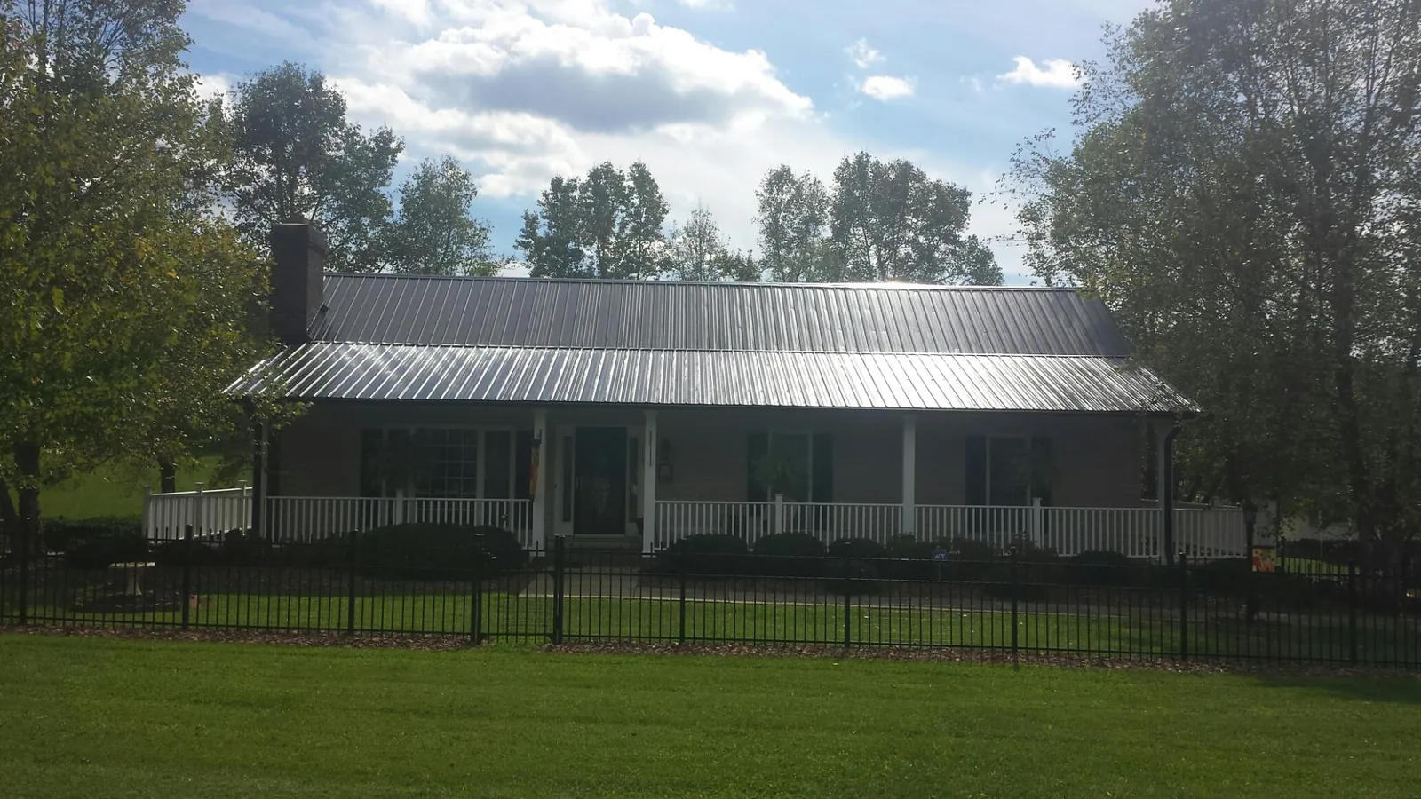 Gray metal roof on a brick ranch with a full width front porch — Gutter Guard Installation work by our crew in Picacho